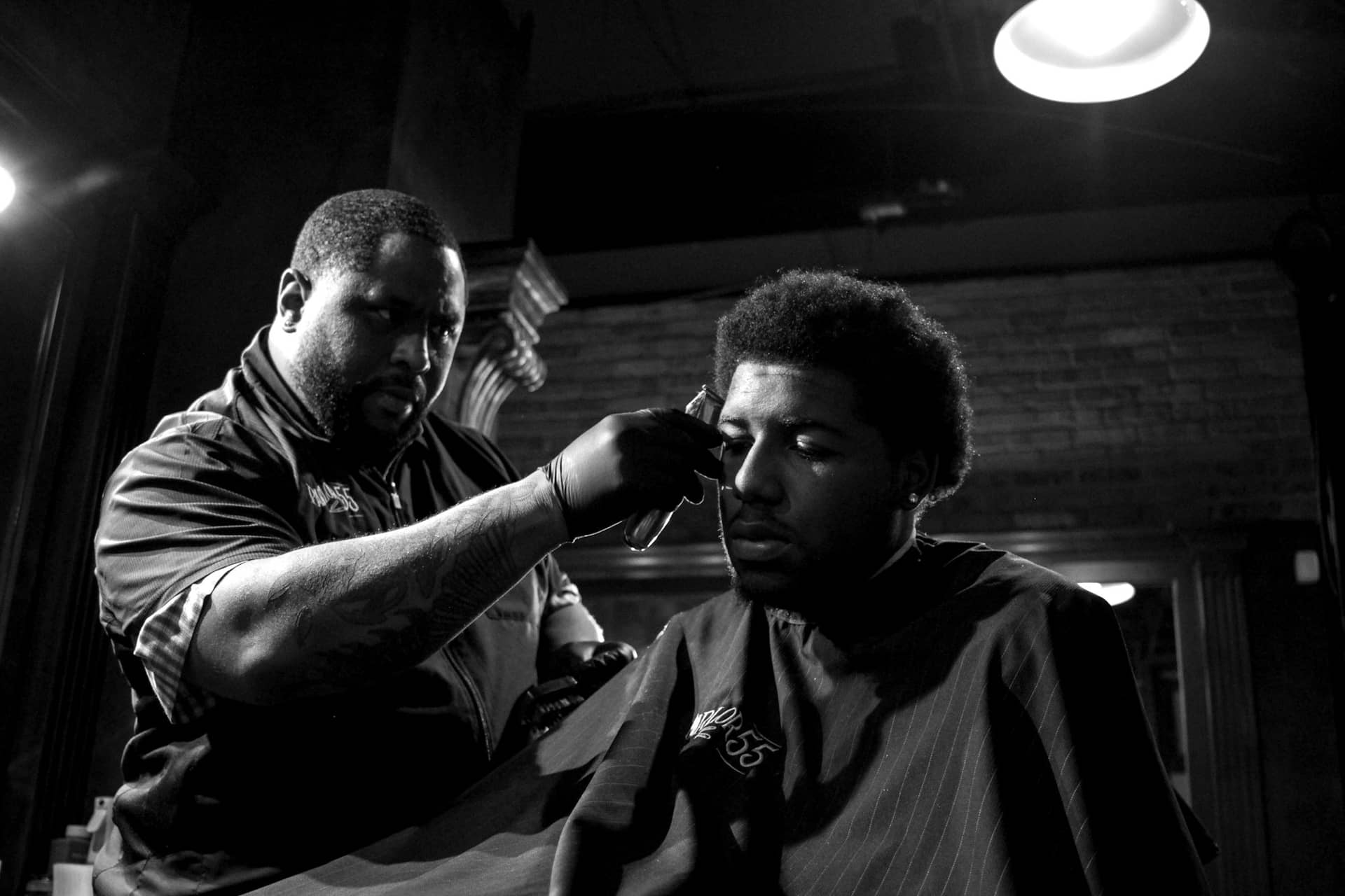 Barbier tatoué qui réalise une coupe à un client dans un salon