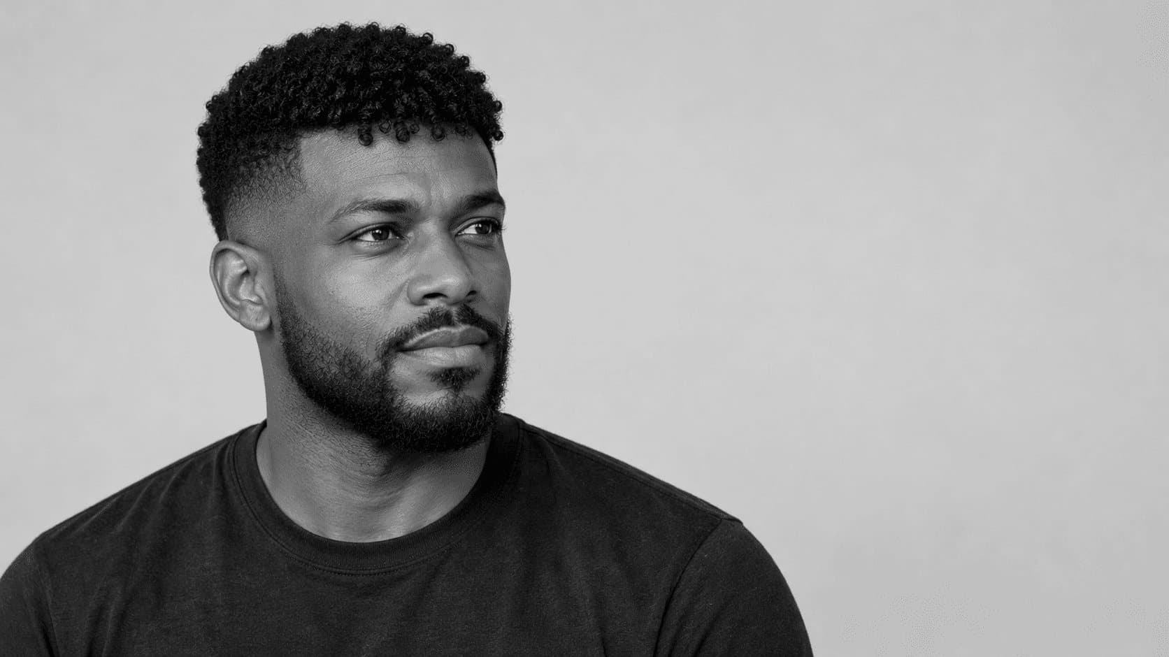 Homme avec un French crop texturé : frange de boucles courtes ramenée vers l’avant et dégradé sur les côtés