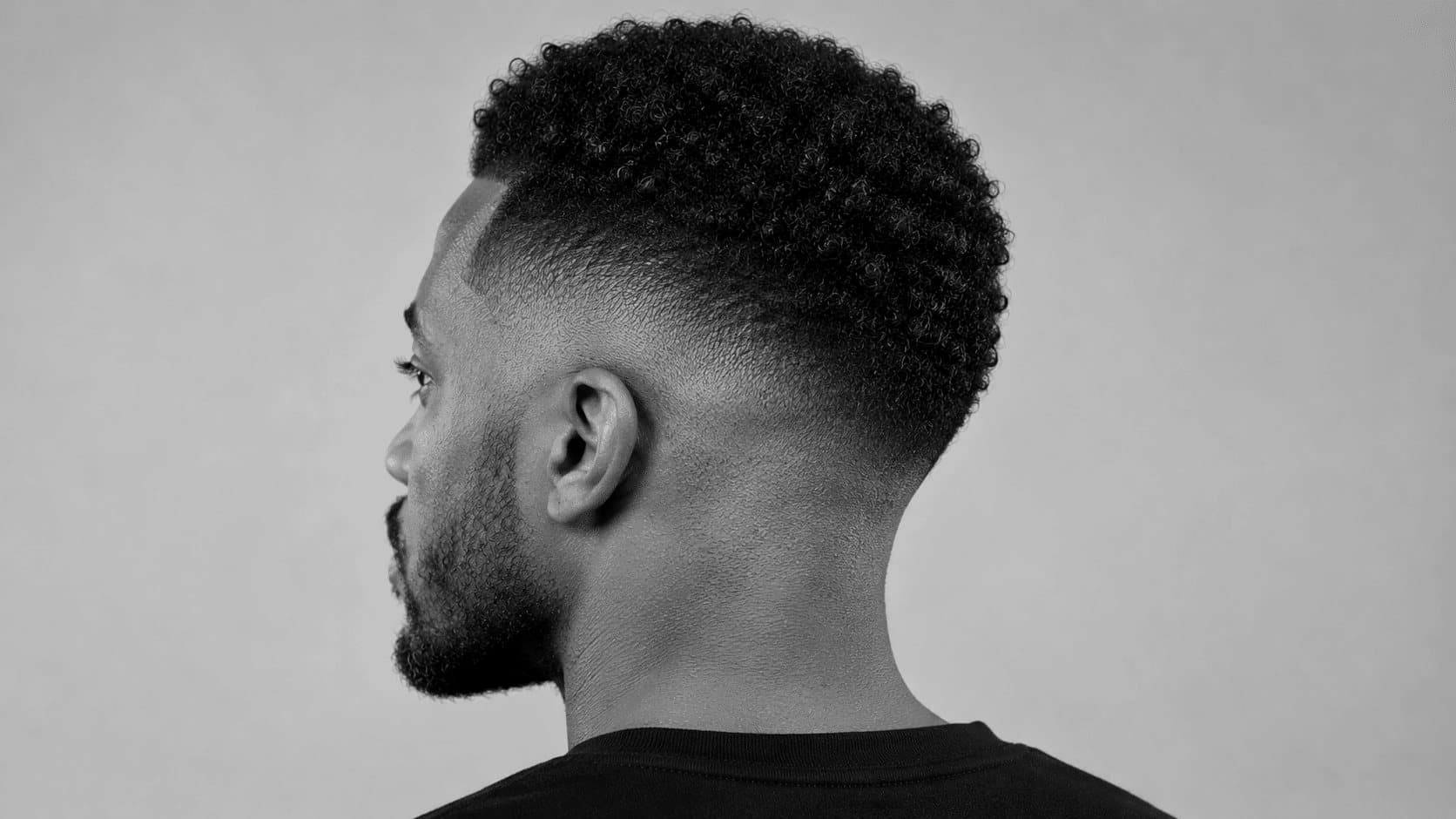 Homme de dos et de profil avec un high fade net : peau rasée sur les côtés et la nuque, dessus bouclé