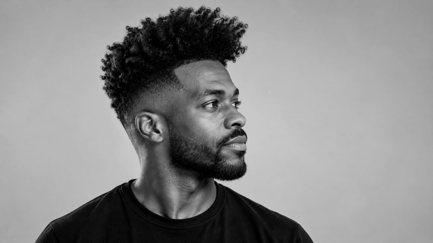 Homme de profil avec un quiff volumineux et décoiffé sur un high fade